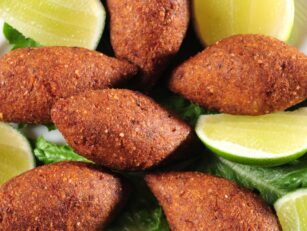 A close up of fried kibbe with limes from a Middle Eastern food truck