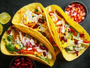 Tasty appetizing tacos with chicken, vegetables and sauce served on dark background. Top View.